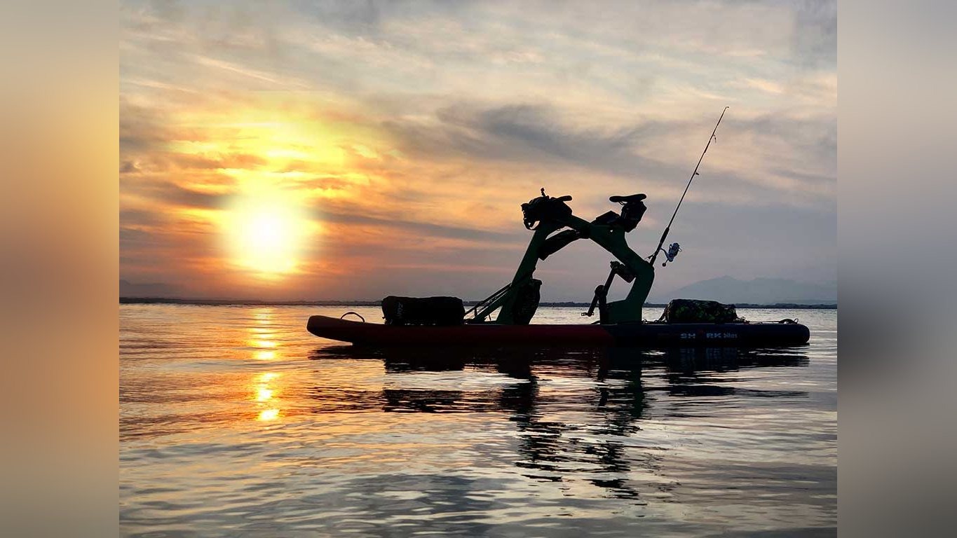 Red Shark Adventurer met hengel silhouet tegen een zonsondergang op het water