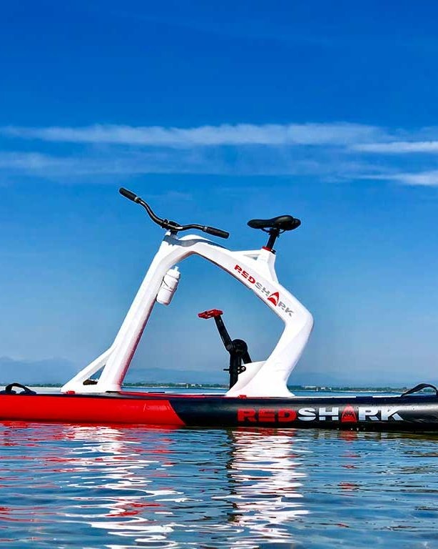 Witte Red Shark Bike Enjoy op spiegelglad water onder een blauwe lucht