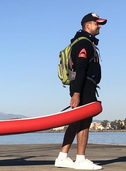 Man draagt een opgerold Red Shark board met de Red Shark rugzaktas op zijn rug