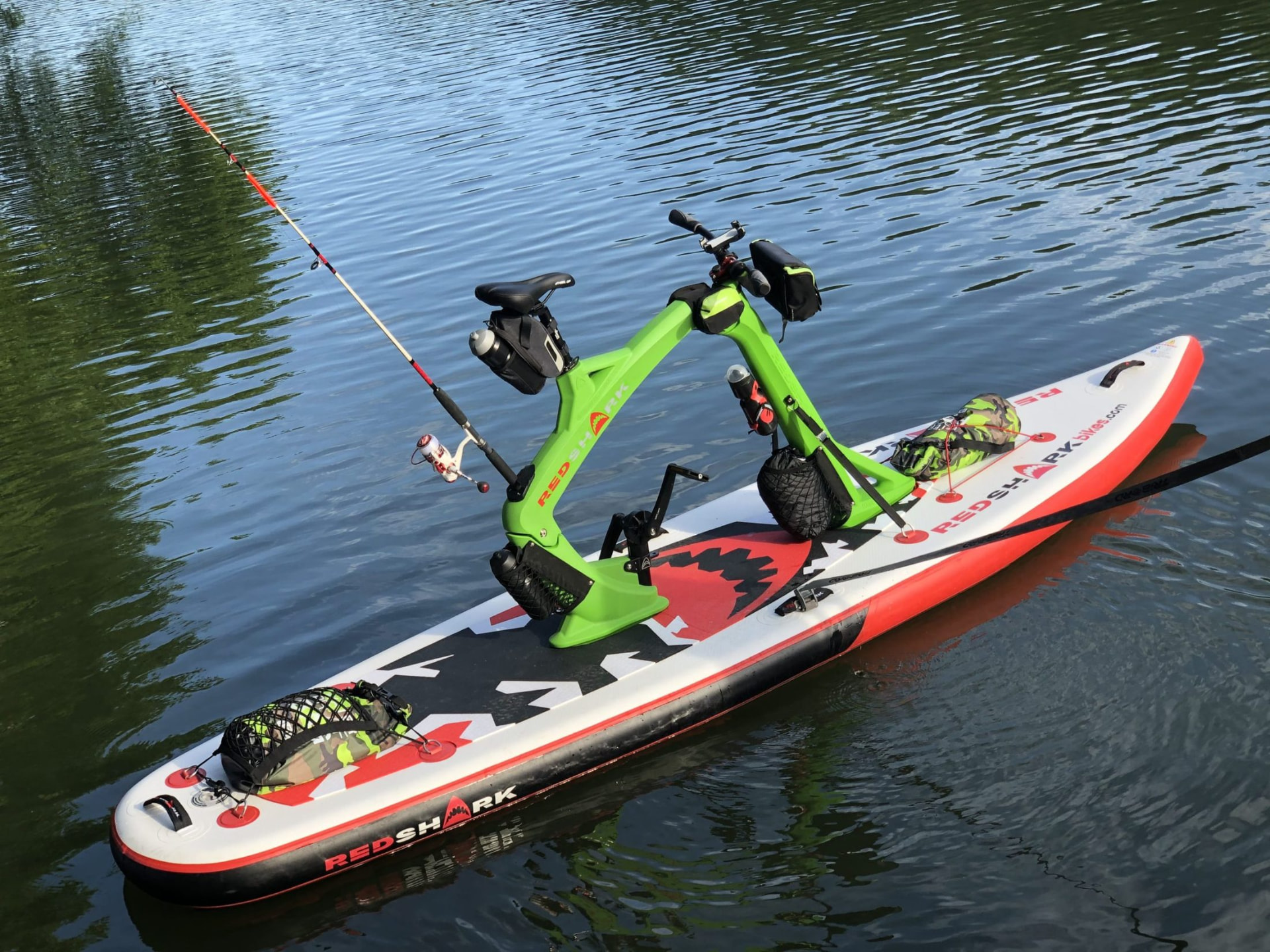 Groene Red Shark waterfiets met hengel op rustig water met spiegeling