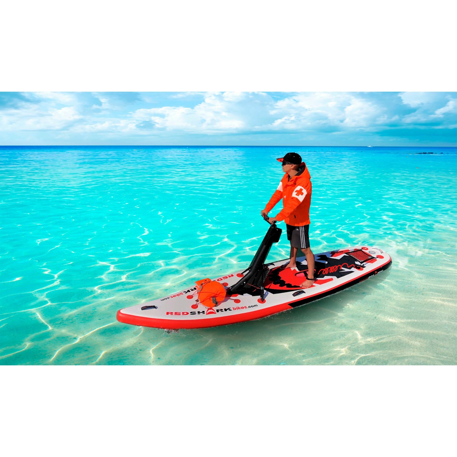 Staande rijder op een Red Shark E-Scooter in helder turquoise water