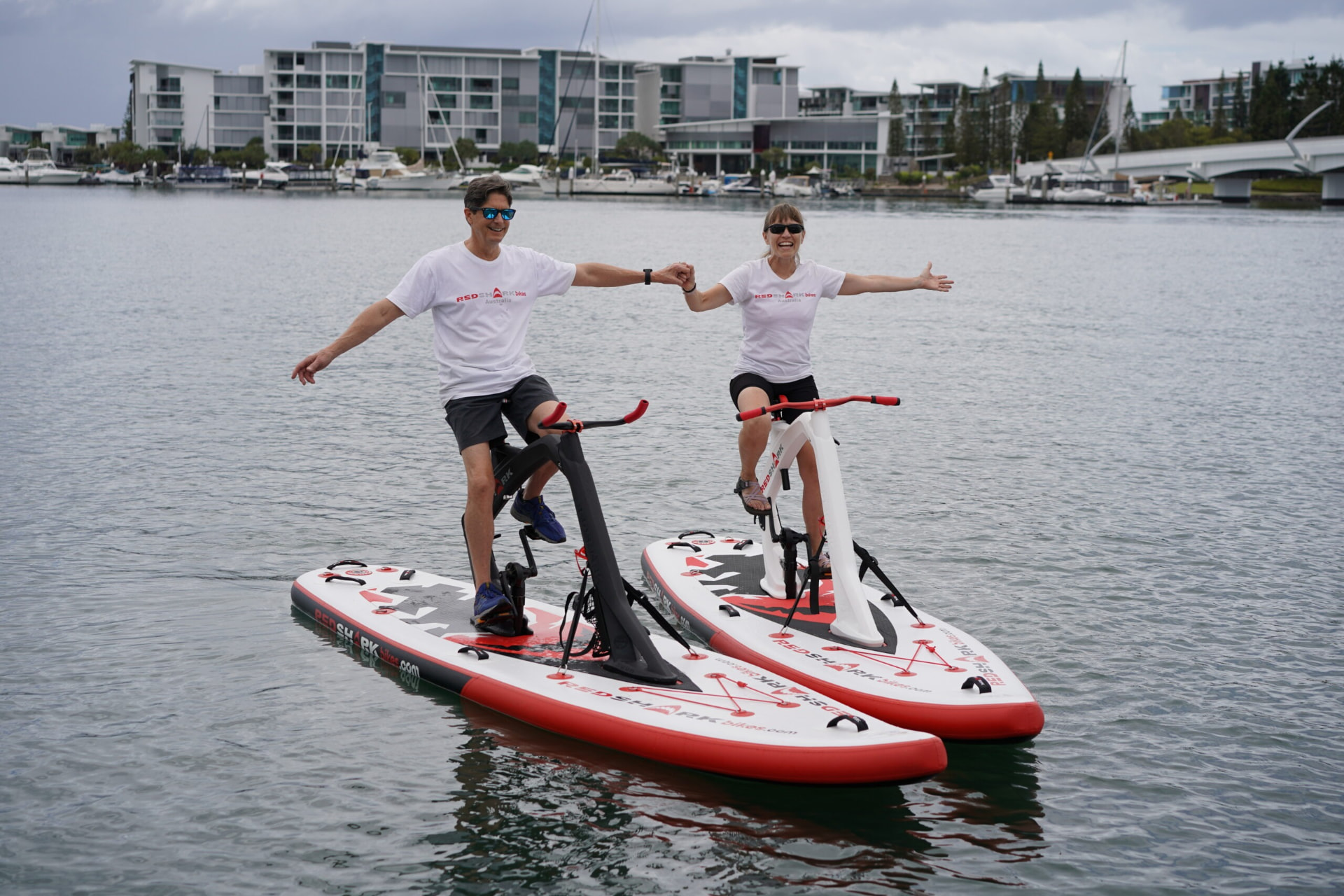 Twee lachende rijders naast elkaar op Red Shark waterfietsen tijdens een rit